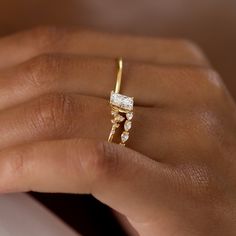 a woman's hand wearing a gold ring with three stones on the band and a diamond set in the middle