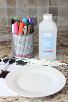 a white plate sitting on top of a kitchen counter next to markers and pencils