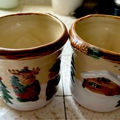 two brown and white cups sitting on top of a tiled counter next to each other