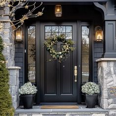 a black front door with two planters on the steps