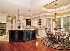 a large kitchen with an island and dining table next to the stove top oven in it