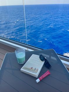 a book and sunglasses on a table in front of the ocean