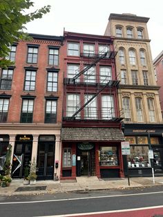 an old brick building on the corner of a street in front of tall buildings with balconies