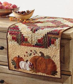 an image of a quilted table runner on a dresser with apples in the background