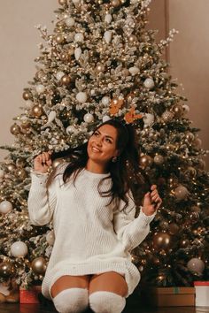 a woman sitting in front of a christmas tree