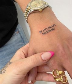 a woman's wrist with a tattoo saying by any means necessary