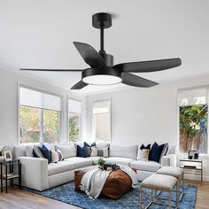 a living room with white couches and black ceiling fan