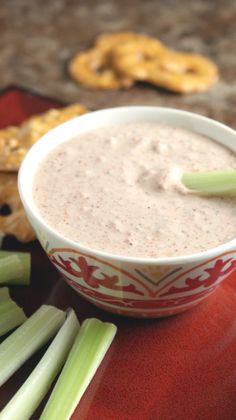 celery sticks and dip in a bowl with pretzels on the side