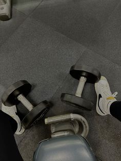 a person standing next to a pair of dumbbells on the ground with their feet propped up