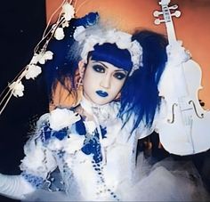 a woman with blue hair and makeup holding a violin