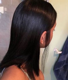 a woman is brushing her long hair in the bathroom with an electric toothbrush and soap dispenser