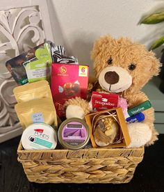 a brown teddy bear sitting in a basket filled with food and candy items on top of a table