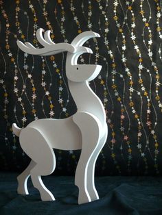 a white wooden reindeer standing on top of a blue sheet covered floor next to a wall