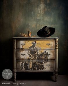 an old dresser with a cowboy painting on the front and sides, next to a hat