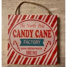 the north pole candy cane factory sign is hanging on a wooden table with rope around it