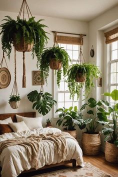 a bedroom with lots of plants hanging from the ceiling and bed in front of two windows