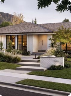 a white house with steps leading up to it's front door and grass in front