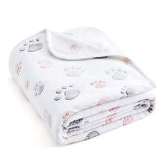 a white blanket with paw prints and pink dots on the bottom is folded in half