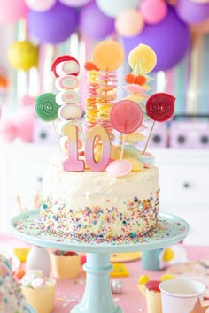 a birthday cake with colorful candies and balloons in the background