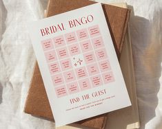 the bridal bingo game is sitting on top of two books, one pink and one brown