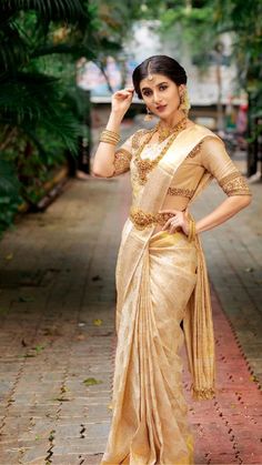 a woman in a gold sari posing for the camera