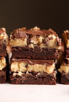 several pieces of chocolate cake with white and brown frosting on top, stacked together