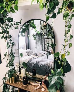 a mirror sitting on top of a wooden table next to a plant covered wall in a bedroom