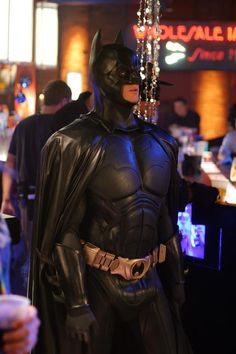 a man dressed as batman standing in front of a bar