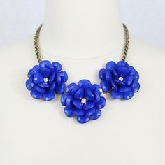 "A beautiful flower bib necklace featuring three lovely roses.The flowers are made of high quality resin with a rhinestone in the middle. The diameter of the largest flower is 2 1/8\", and the diameter of the smallest flower is 2\". Adjustable brass chains with a vintage touch. Necklace measures 19\". Lead and nickel free.  More colors and styles here: https://www.etsy.com/shop/HelensCollection?section_id=13703310&ref=shopsection_leftnav_2 Our store front: https://www.etsy.com/shop/HelensCollect Blue Flower Necklace, Beaded Rose, Blue Statement Necklace, Flower Statement Necklace, Navy Blue Flowers, Blue Beaded Necklace, Necklace Collar, Statement Bib Necklace, Necklace Chunky