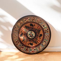 a decorative plate sitting on top of a wooden table next to a white brick wall