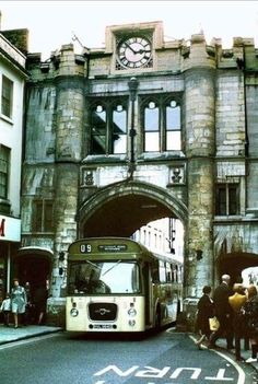 a bus is parked in front of an old stone building with a clock on it