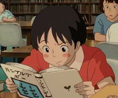 a young boy reading a book in front of other children sitting at desks with bookshelves