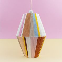 a multicolored wooden lamp hanging from a pink wall