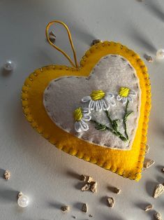 a heart shaped ornament with daisies on it