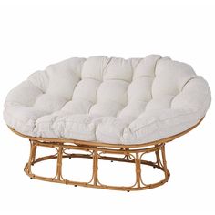 a round wicker chair with white cushions on it's seat cushion and wooden frame