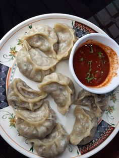 dumplings on a plate with dipping sauce