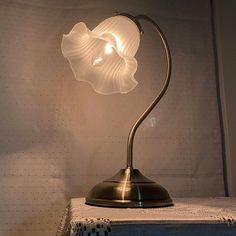 a lamp that is sitting on top of a white table cloth in front of a wall