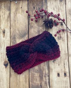 a pair of knitted mittens sitting on top of a wooden floor next to berries