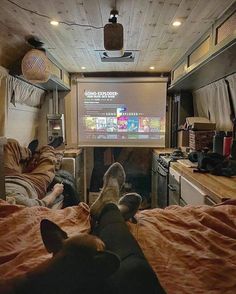 two people and a dog in a camper with a projector screen on the wall