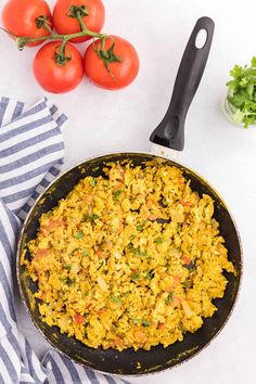 a skillet filled with rice and tomatoes next to some parsley on the side