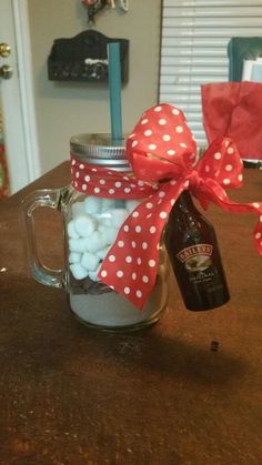 a mason jar filled with marshmallows and a bottle of beer sitting on top of a table