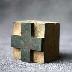 a small wooden cross sitting on top of a table next to a piece of wood