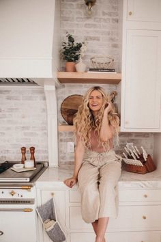 a woman sitting on top of a kitchen counter