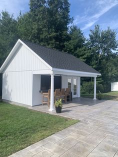 a small white shed sitting on top of a lush green field