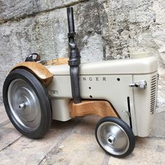 an old fashioned wooden toy tractor sitting on top of a stone floor next to a wall