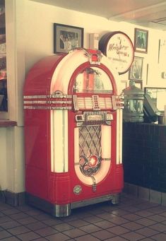 an old fashioned red and white jukebox sitting on the floor in a restaurant