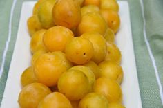 a white plate filled with yellow fruit on top of a green tablecloth covered table