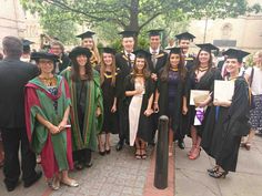 a group of people in graduation gowns and caps posing for a photo on the sidewalk