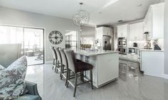 a kitchen with white cabinets and marble counter tops next to a dining room table filled with chairs