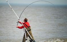 a man holding onto a fishing pole while standing in the water